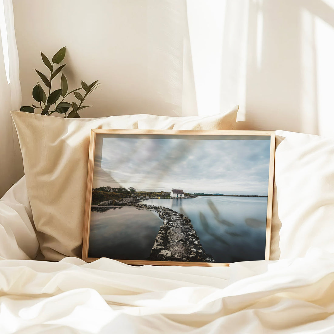 Connemara bothy framed print resting on a bed with sunlight filtering in.