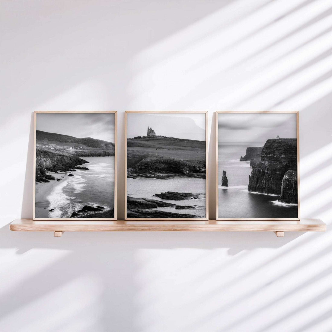 Irish black and white landscape print set of three displayed on a shelf, featuring coastal cliffs and historic landmarks