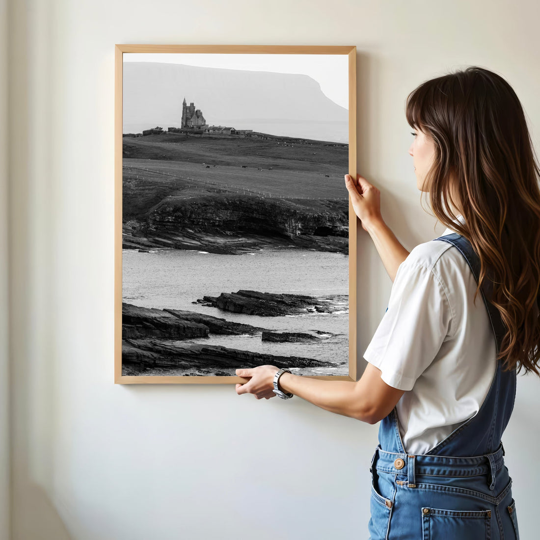 Woman hanging framed Classiebawn Castle print in modern home interior