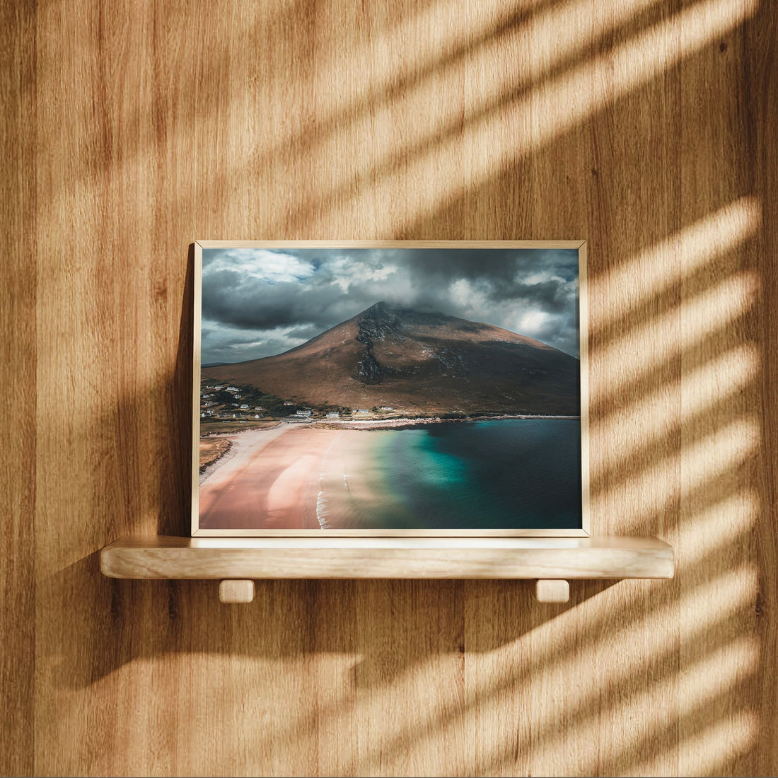 Dugort Beach wall art print on a shelf with sunlight and wooden textures.