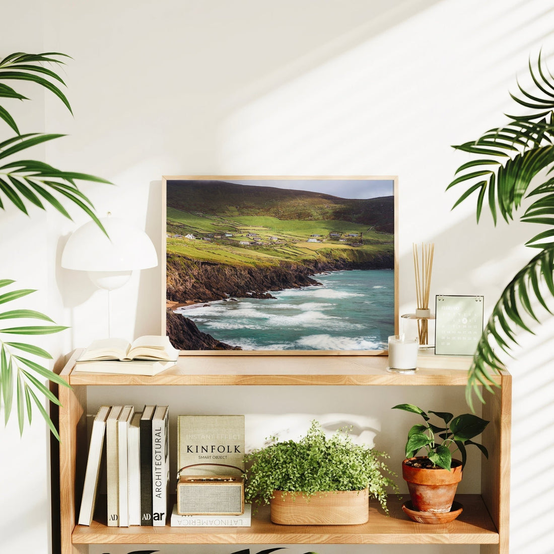 Irish cottage landscape above Coumeenoole Beach displayed in a home interior with plants and books