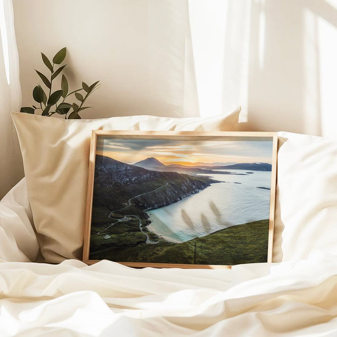 Keem Beach wall art leaning against pillows in a softly lit bedroom