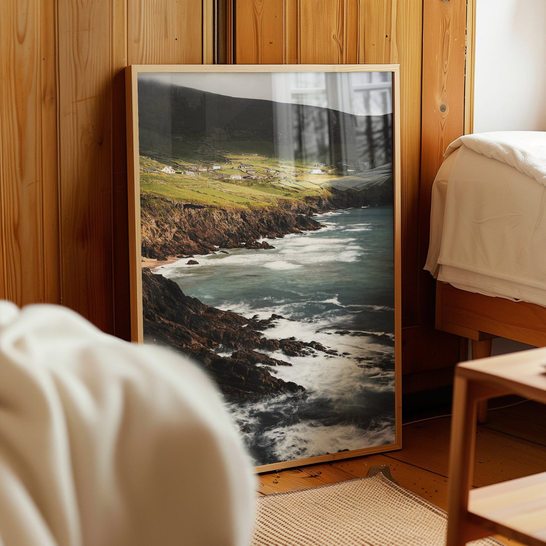 Framed Coumeenoole Beach art print styled in a cosy wooden bedroom corner.