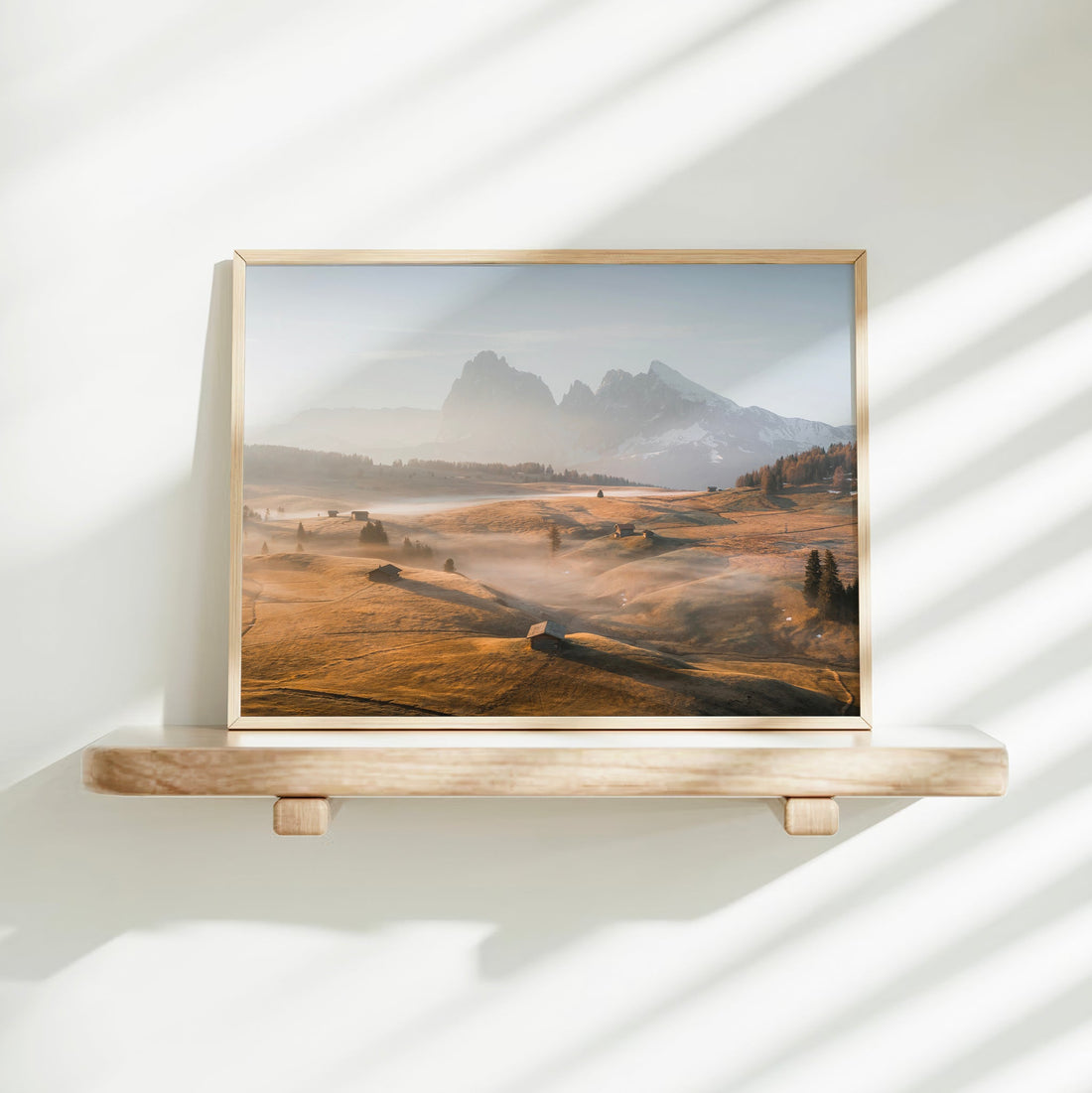 Minimalist shelf decor with Italian Dolomites photo print framed in light wood.