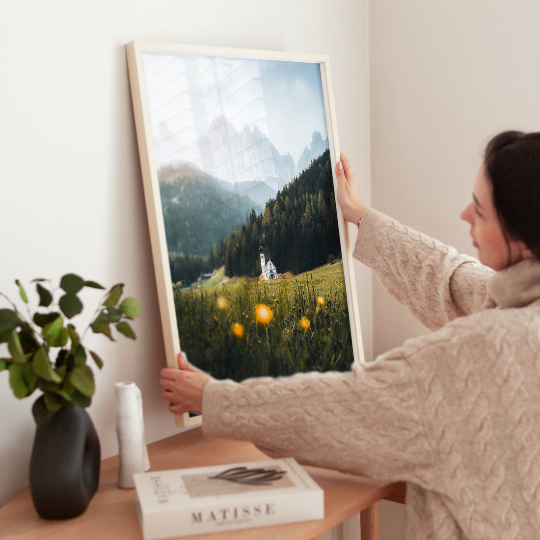 Woman styling a print of St. John’s Church in spring meadow with dramatic mountain backdrop