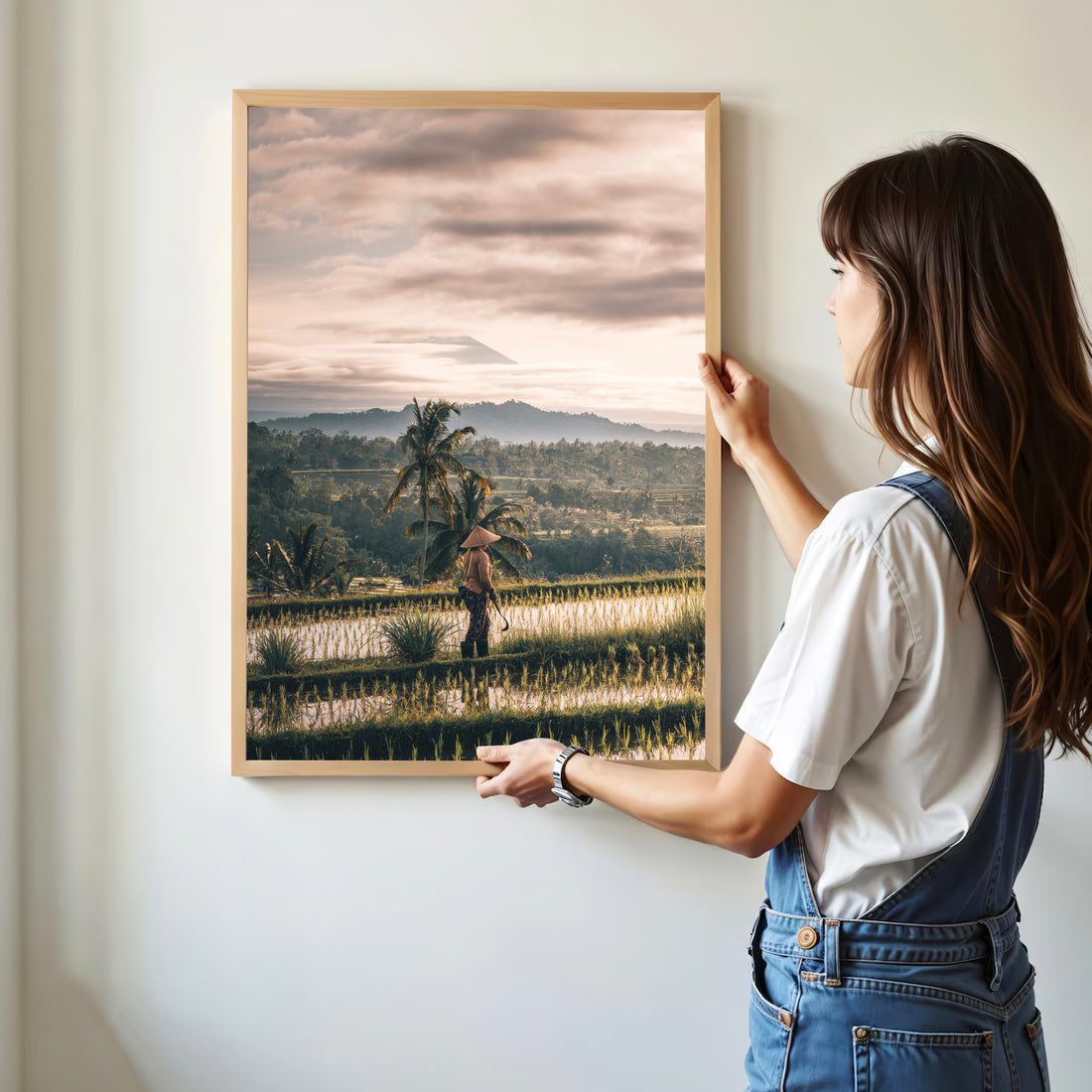 Woman hanging framed Jatiluwih Rice Fields print featuring Mount Agung view