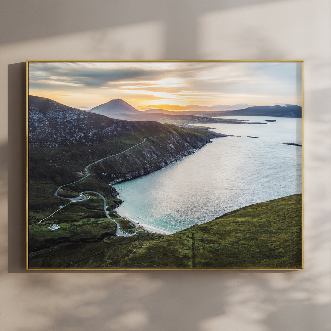 Aerial view of Keem Beach at sunset on Achill Island with winding coastal road and golden light