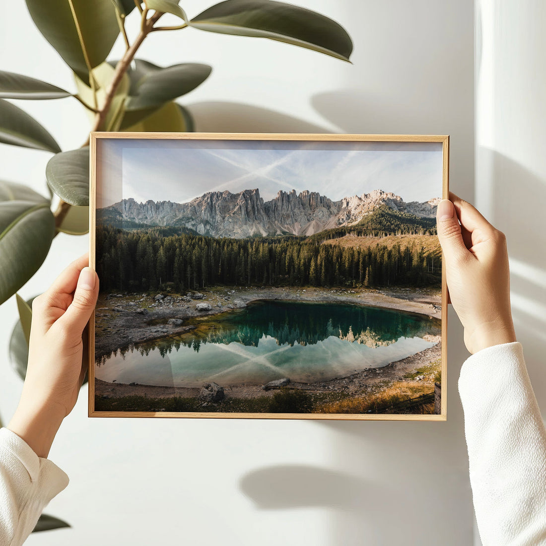 Framed Lago di Carezza print held in hands with natural light and greenery
