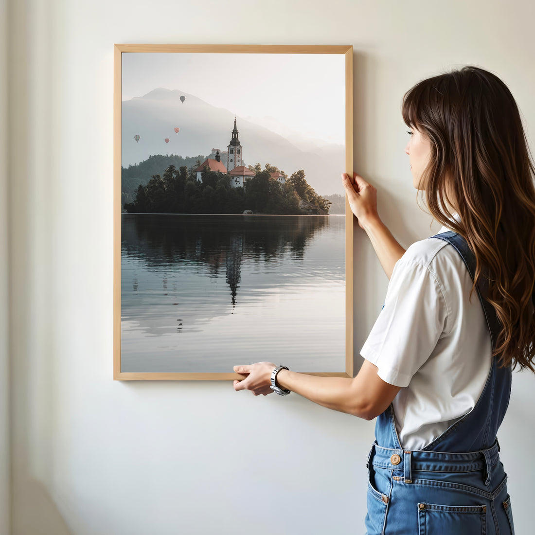 Framed Lake Bled print being held in hands in front of houseplant