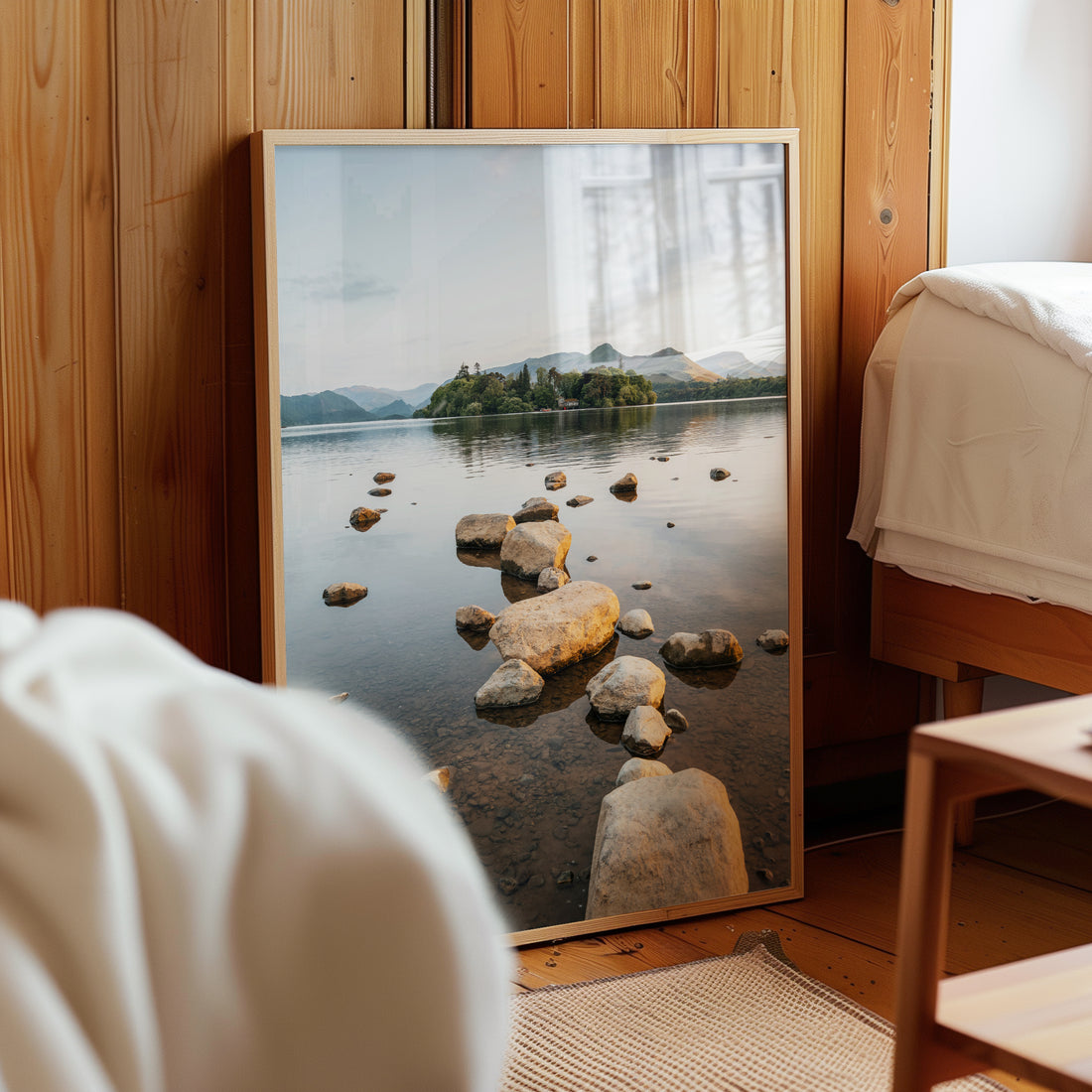 Framed Derwentwater lake print styled in a cosy bedroom with soft wood tones