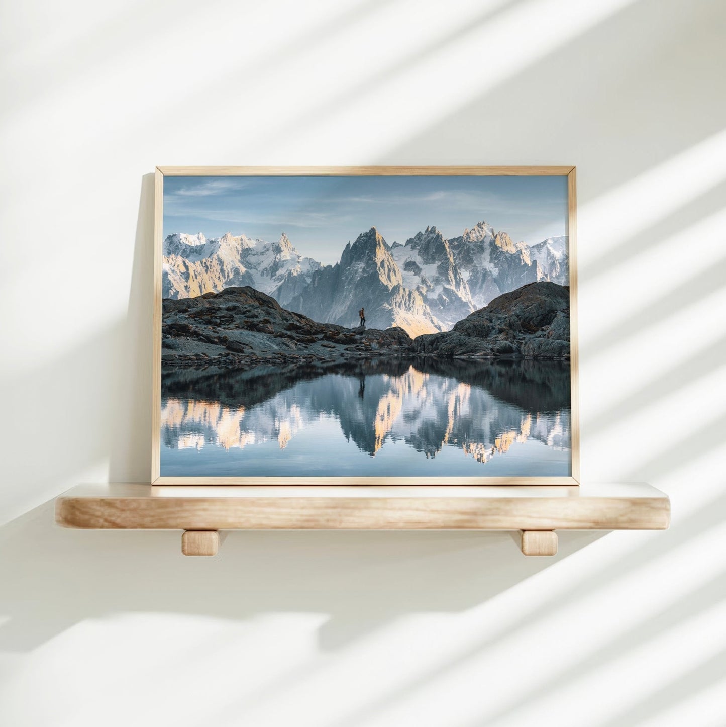 Lake and mountain photography print of a hiker at Lac Blanc, Chamonix with snowy peaks reflected in water.