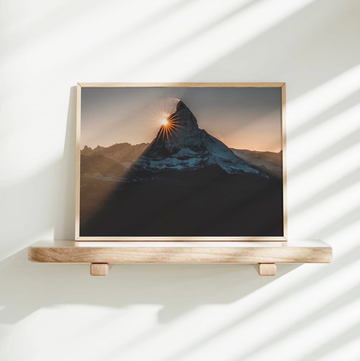 Matterhorn sunburst fine art photo displayed in minimalist white interior with shadows.