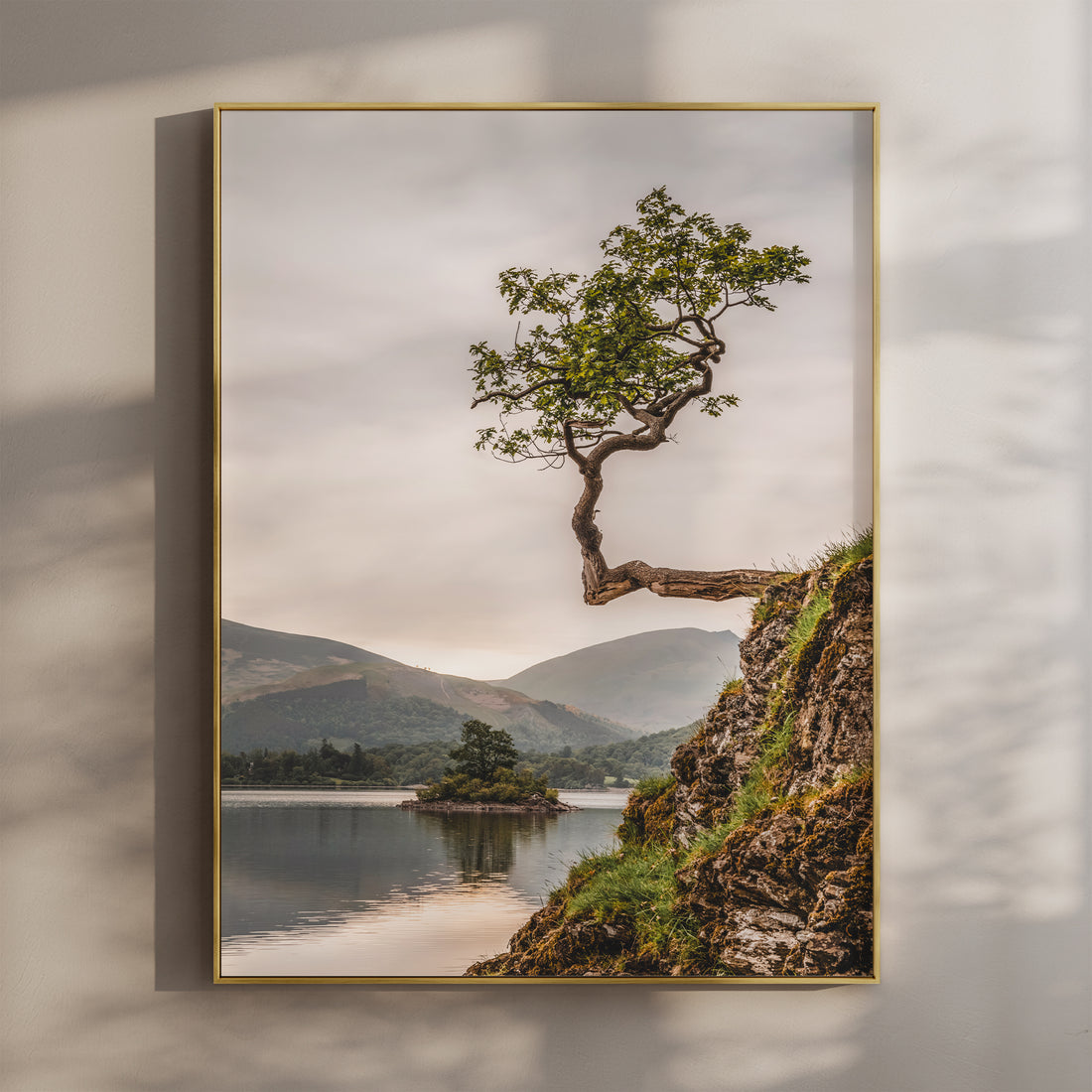 Lone tree on a rocky cliff above Derwentwater with soft pastel skies