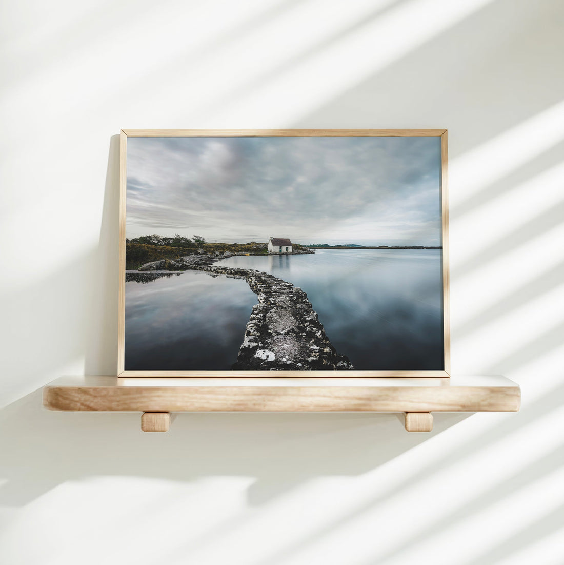 Fisherman’s bothy art print displayed on a floating shelf in soft white light.