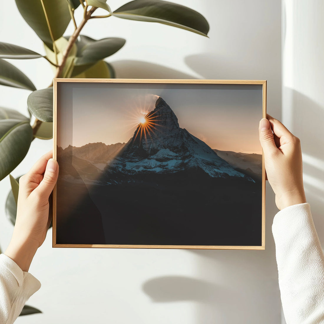 Woman holding framed Matterhorn sunset print in soft natural light.