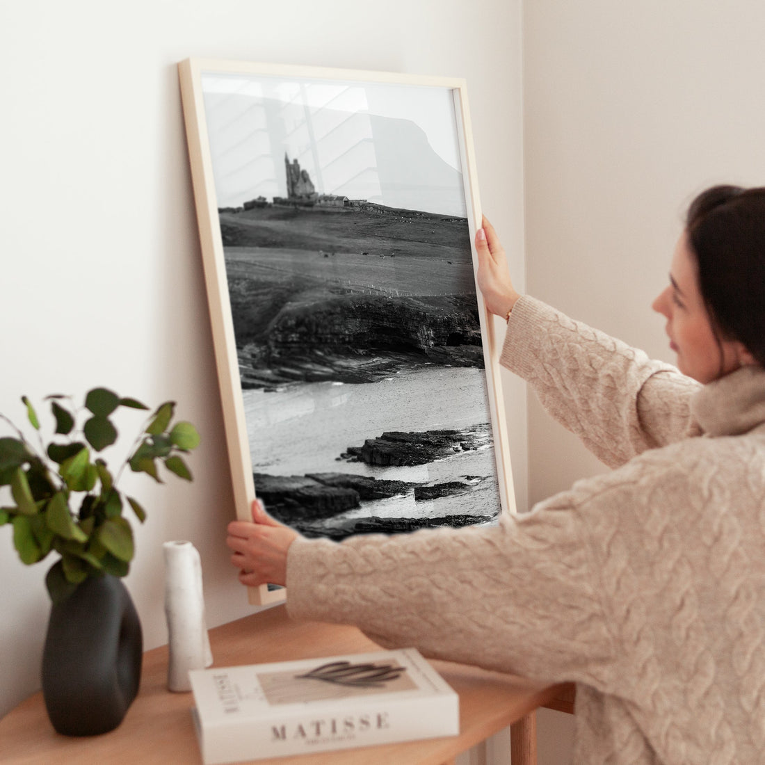 Woman placing Classiebawn Castle photograph on table in Scandinavian-style room