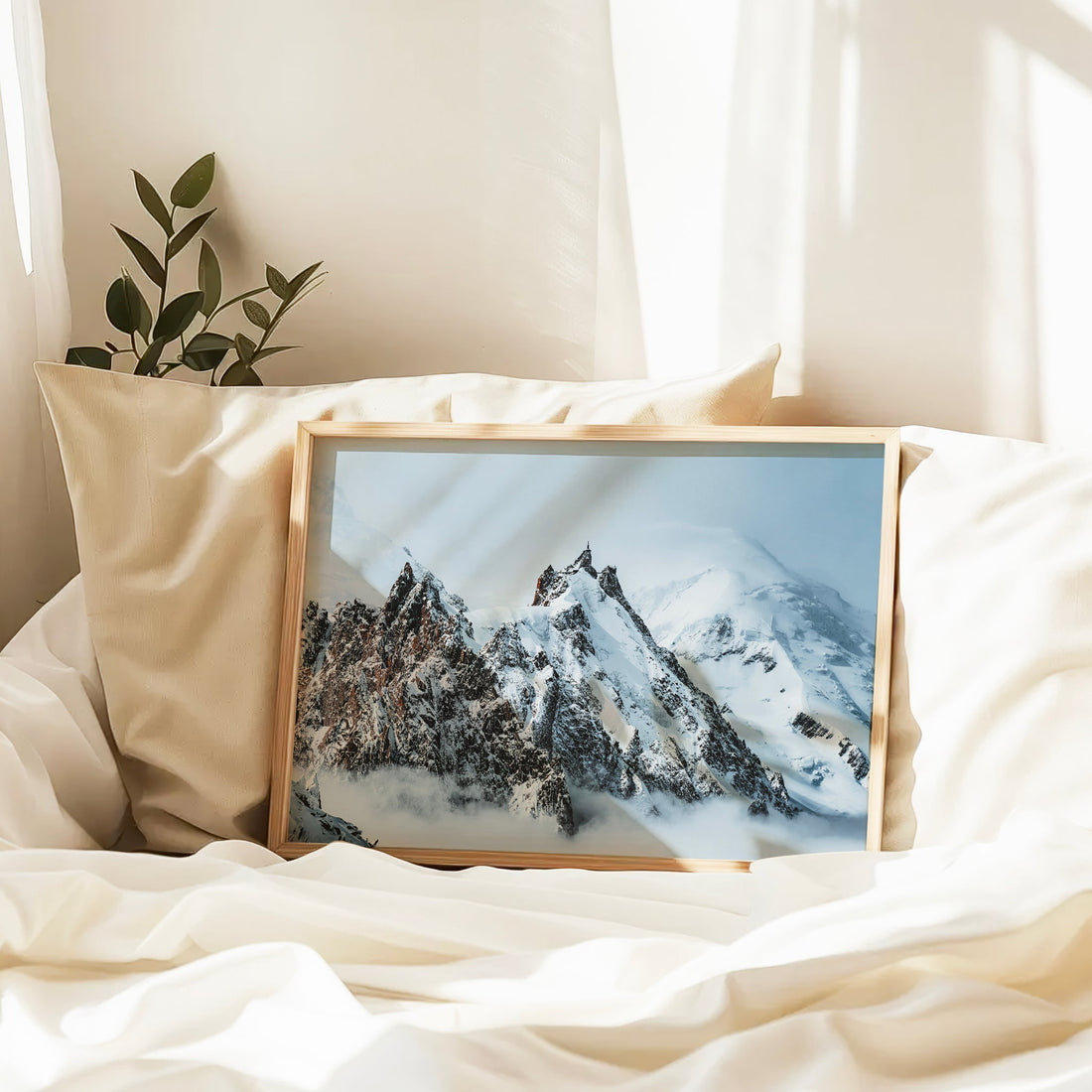 Framed snowy Aiguille du Midi photo print resting on a white bed