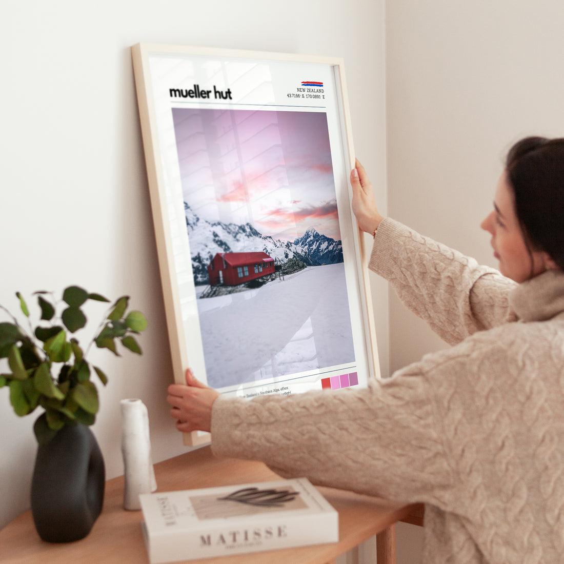 Close-up of Mueller Hut wall art print being held, showing sunrise colours and snowy alpine landscape