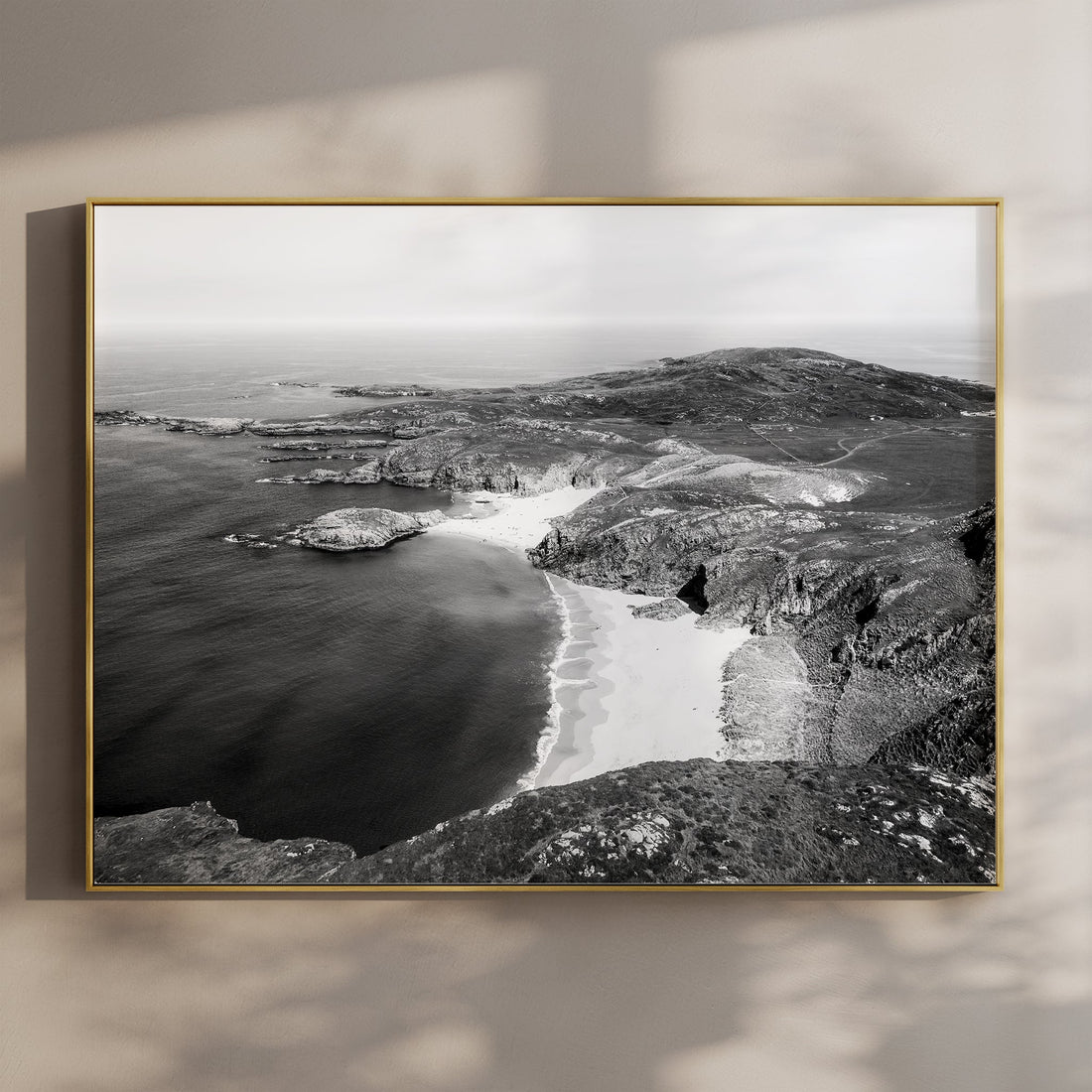 Black and white aerial print of Murder Hole Beach on a wall in soft shadow light.