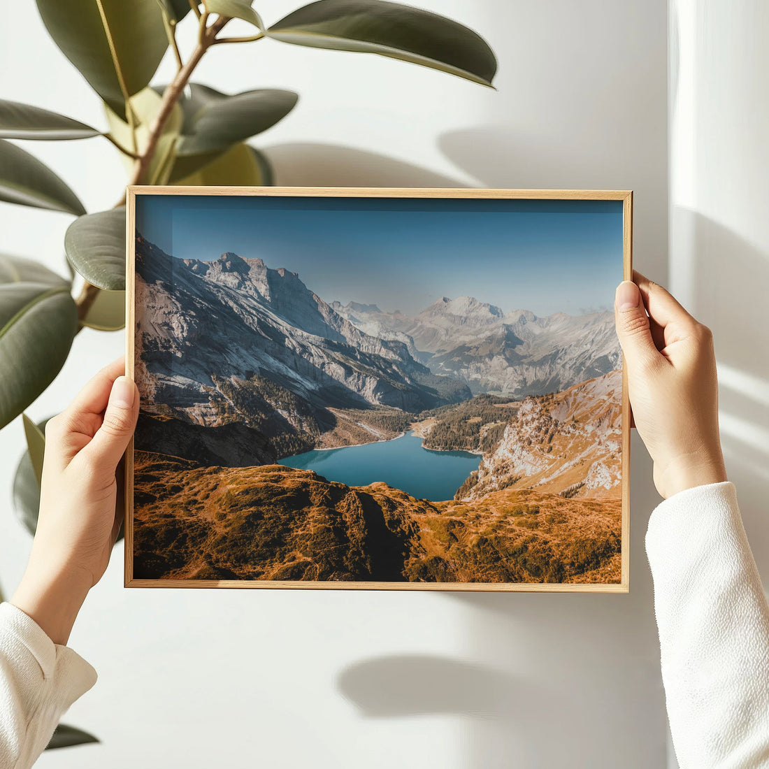 Hands holding a framed Oeschinensee landscape photography print