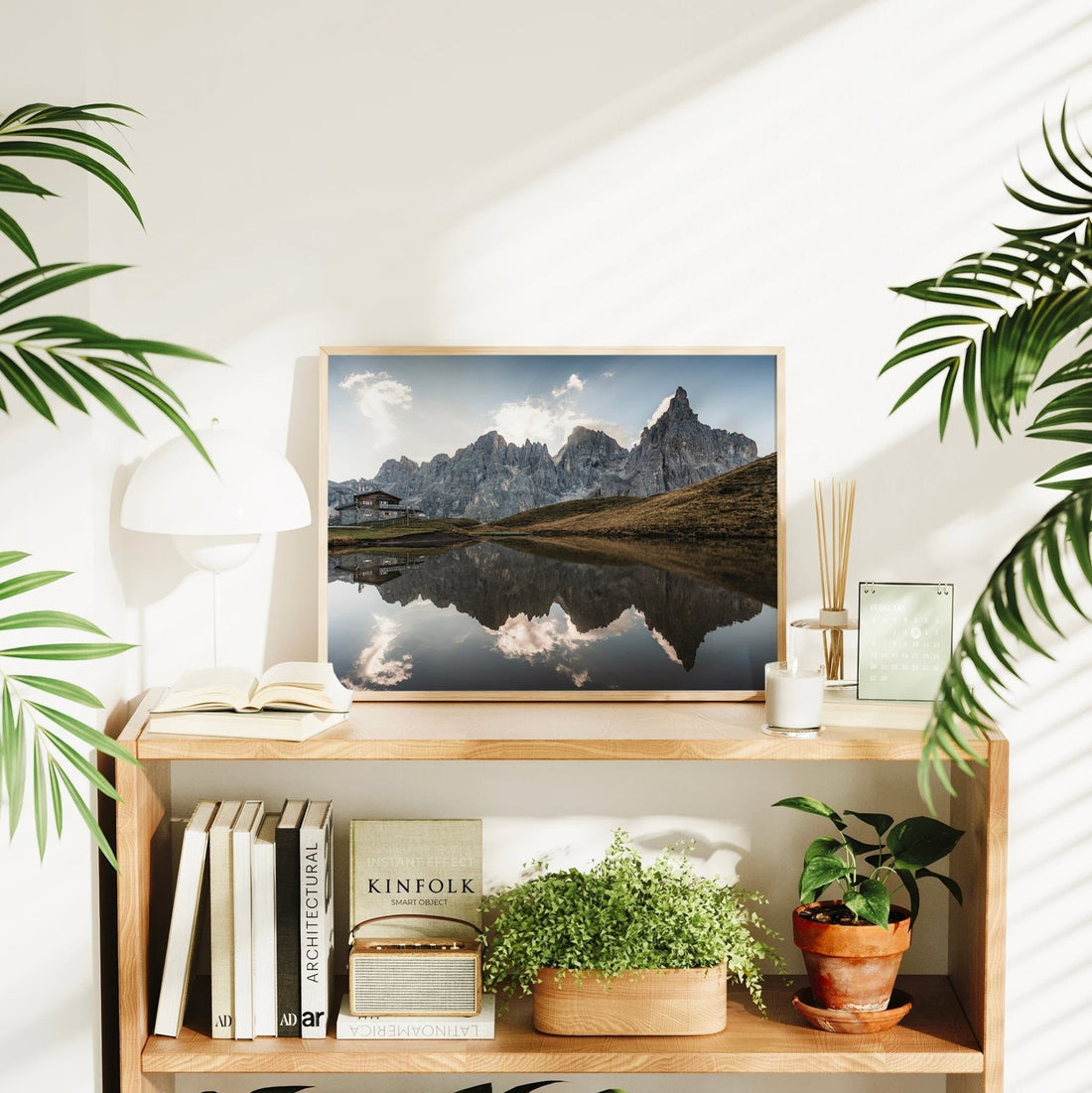 Mountain reflection print of Passo Rolle on shelf surrounded by plants and decor