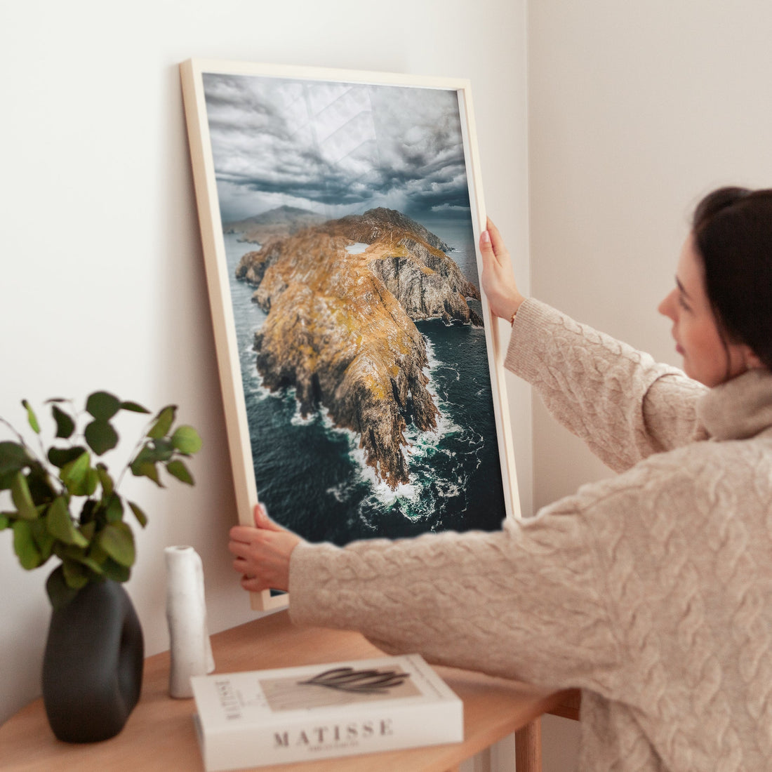 Woman placing Irish landscape print of Sheep’s Head Peninsula on a table in a cosy home.