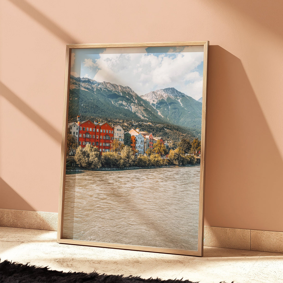 Framed Innsbruck alpine cityscape leaning against a soft peach wall in natural light.