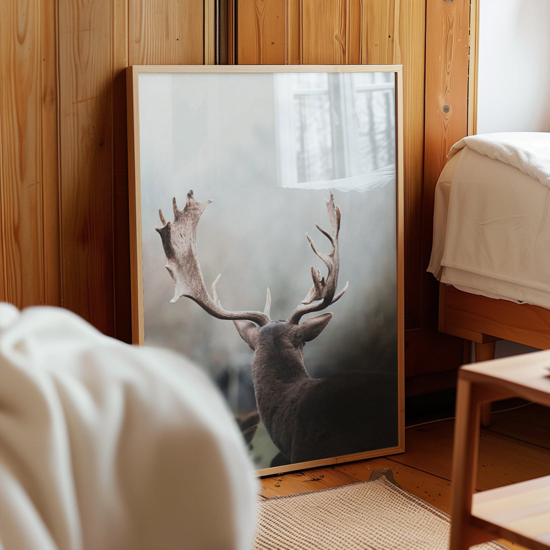 Deer antlers print leaning against wooden wall in a rustic bedroom