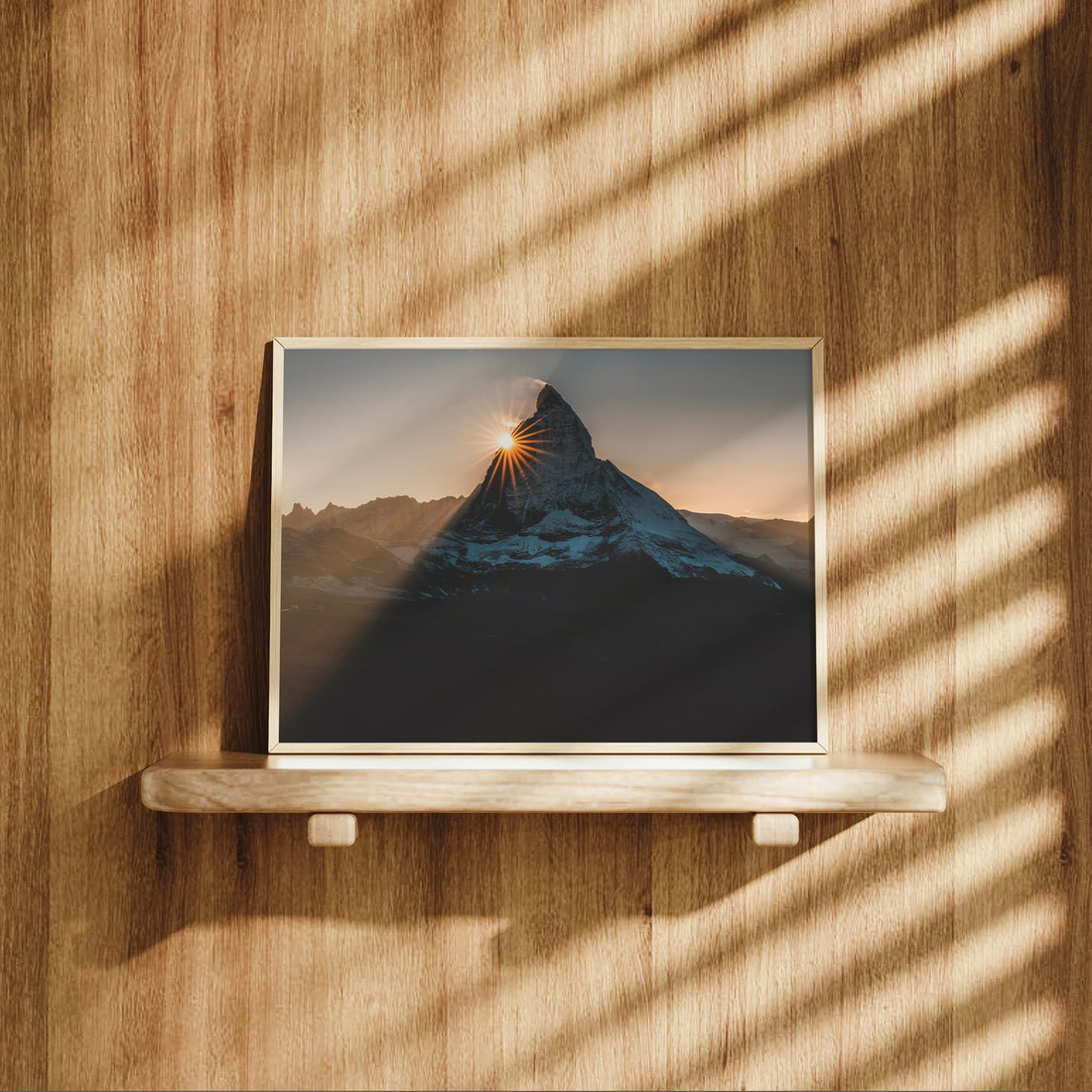Matterhorn sunset print displayed on wooden shelf with dramatic shadows.
