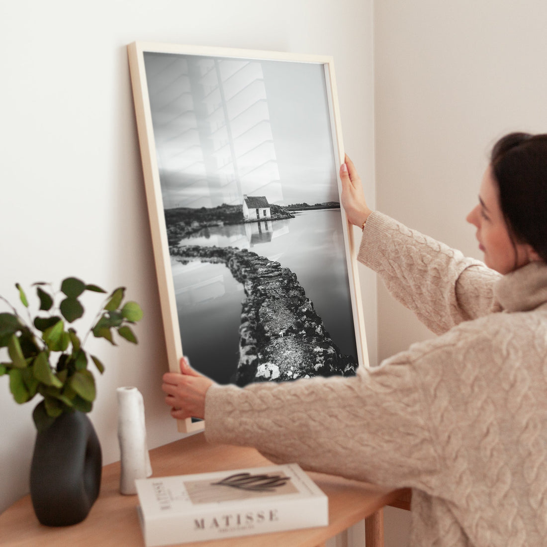 Woman placing a framed Irish cottage photo print on a console table.