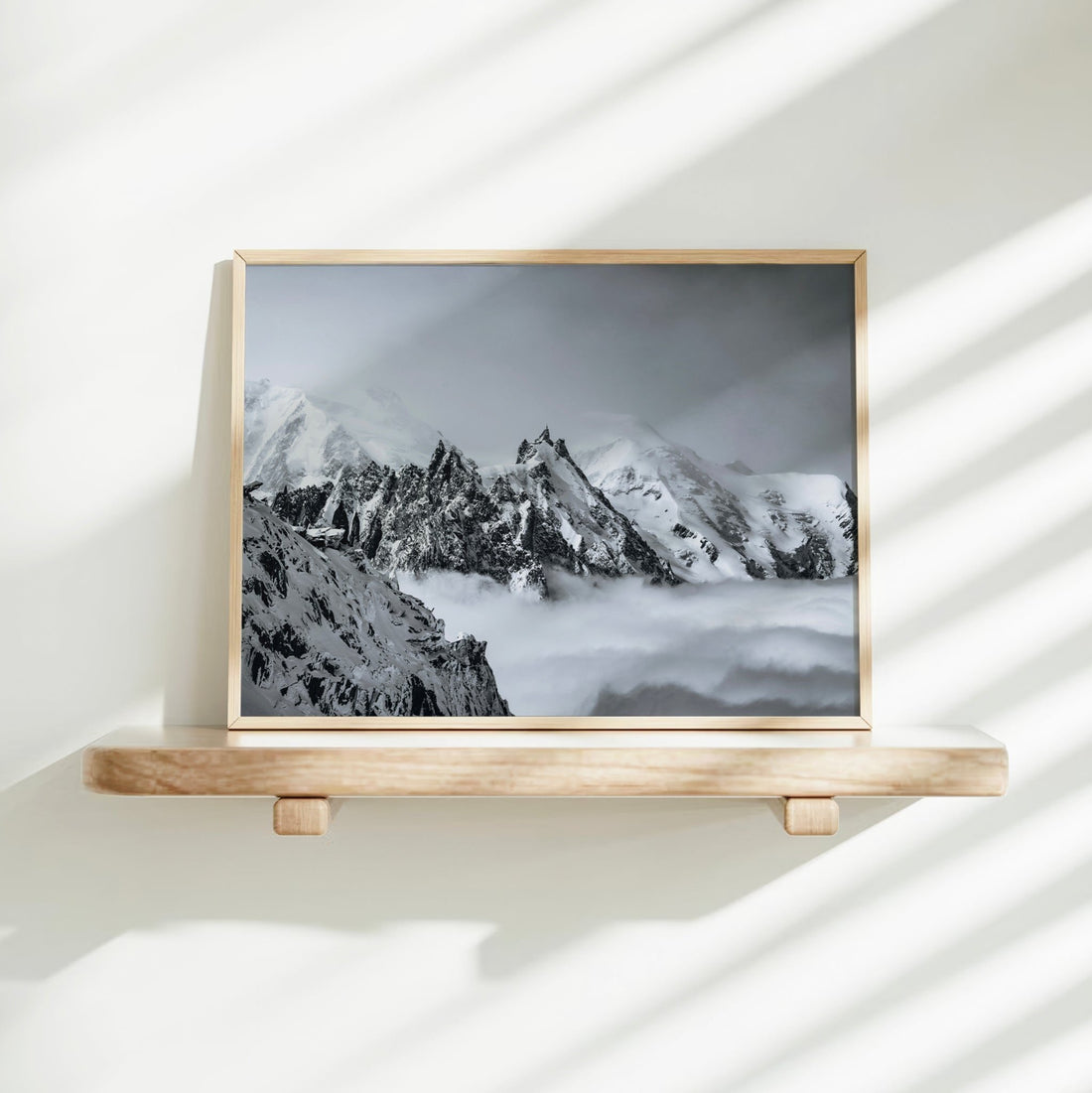A snowy Mont Blanc and Aiguille du Midi print leaning on a white shelf in natural light