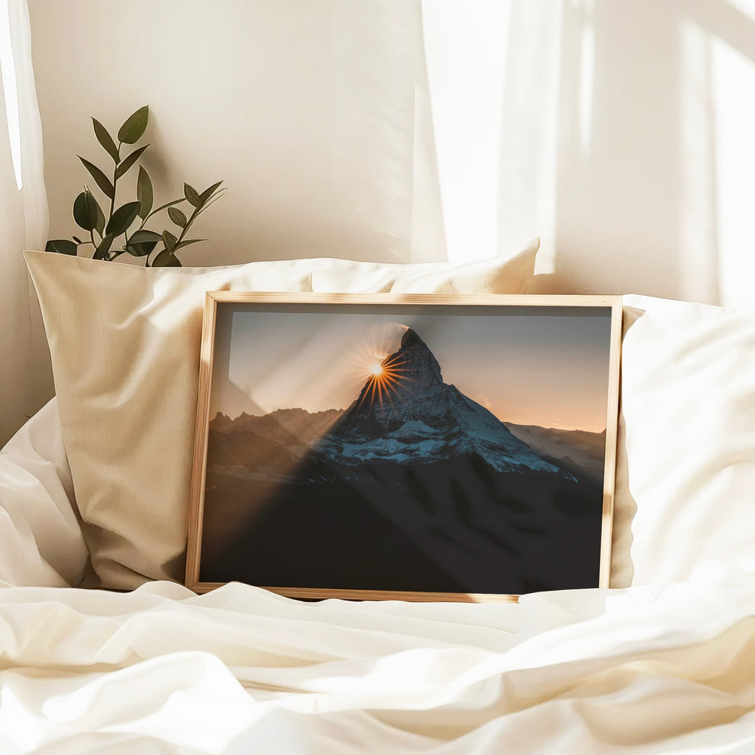 Framed Matterhorn sunset photo print resting on a bed in warm light.