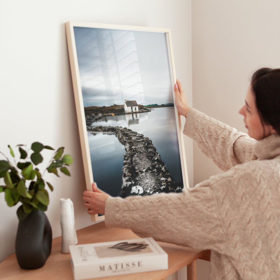 Woman positioning a reflective Irish bothy print on a desk