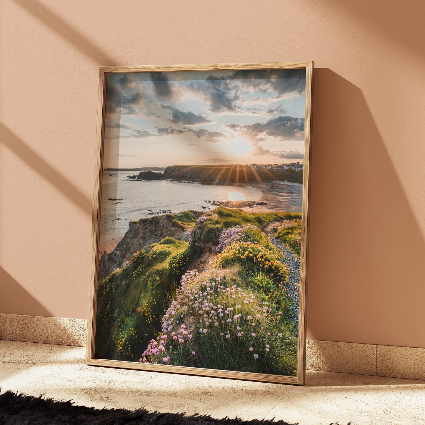 Framed photograph of Annestown Beach propped against a sunlit peach wall with vivid evening tones.