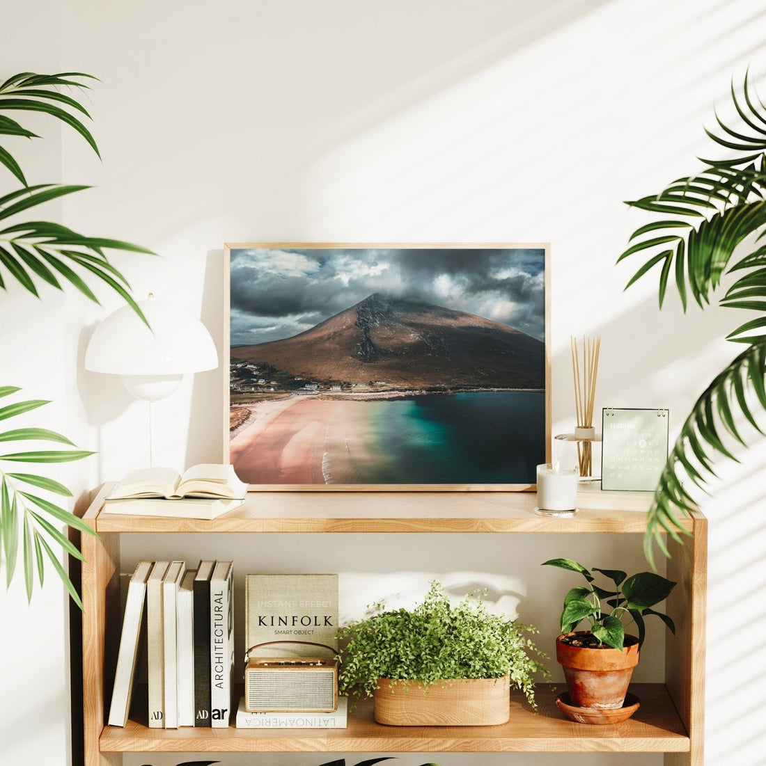 Interior scene with Dugort Beach photo print surrounded by books, plants, and warm decor.