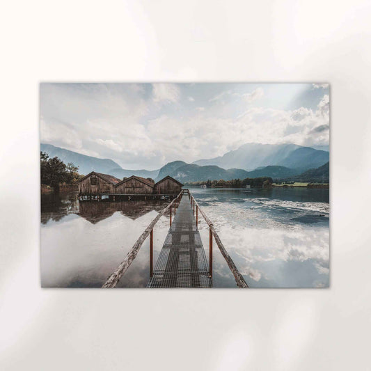 Sunrise light over calm Kochelsee water with alpine peaks and boathouses