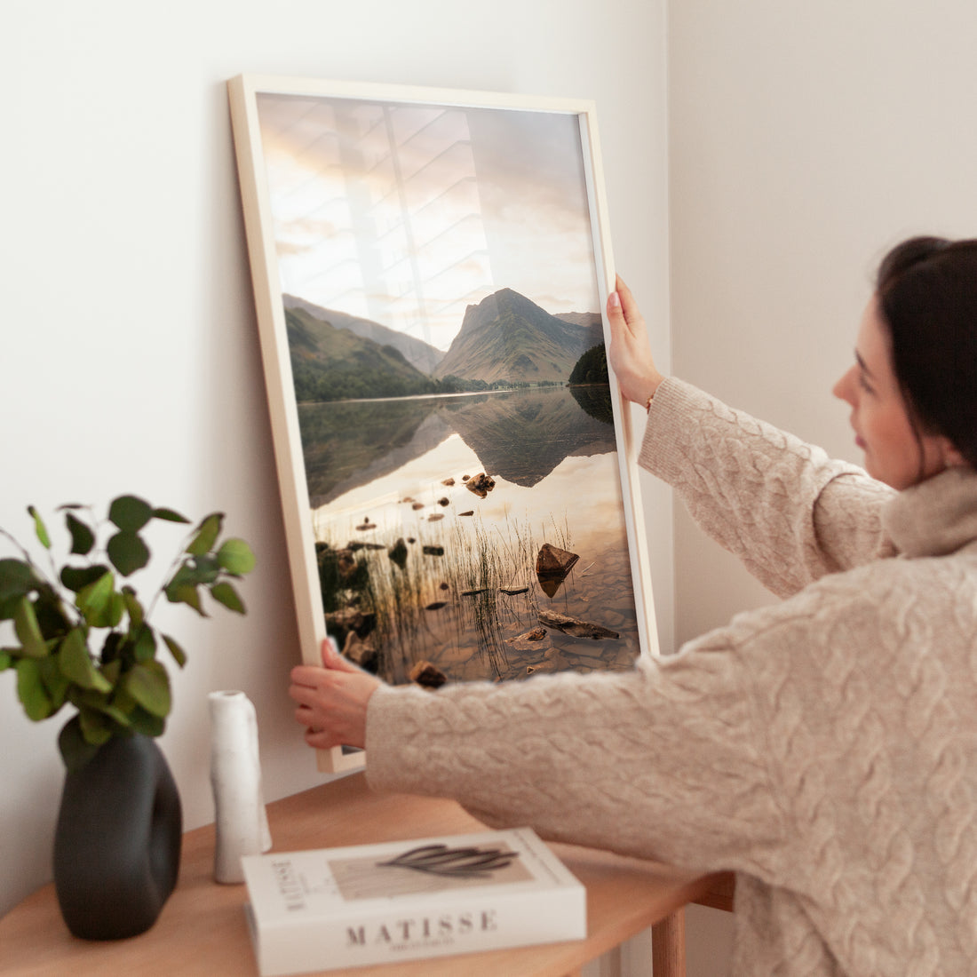 Woman holding Buttermere photo print showing peaceful UK mountain scenery.