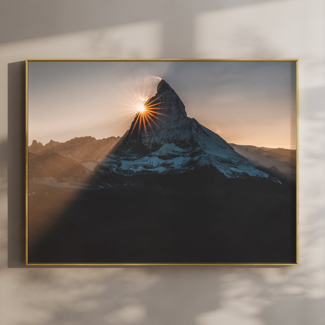 Fine art print of the Matterhorn at sunset with golden sunburst, hanging in a modern interior.