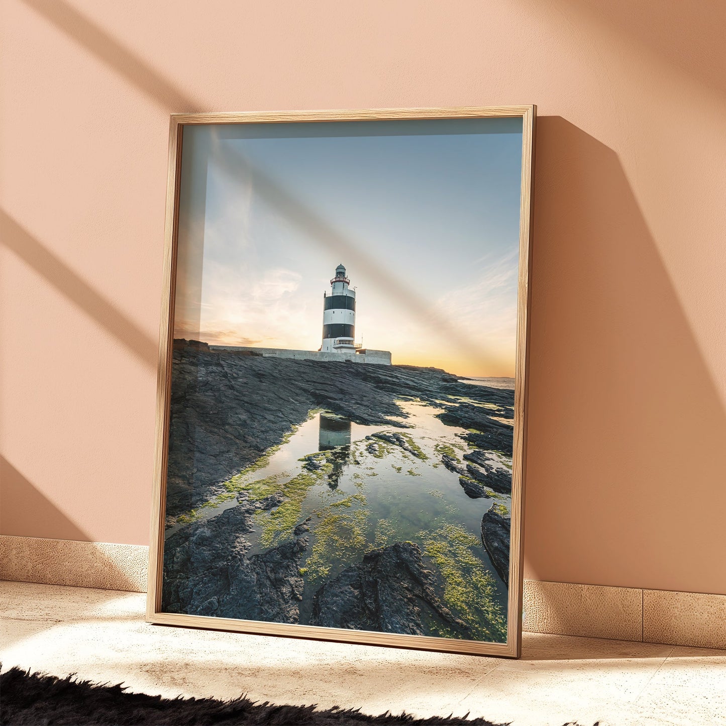 Framed Hook Head lighthouse print in soft peach room, sunset light casting shadows