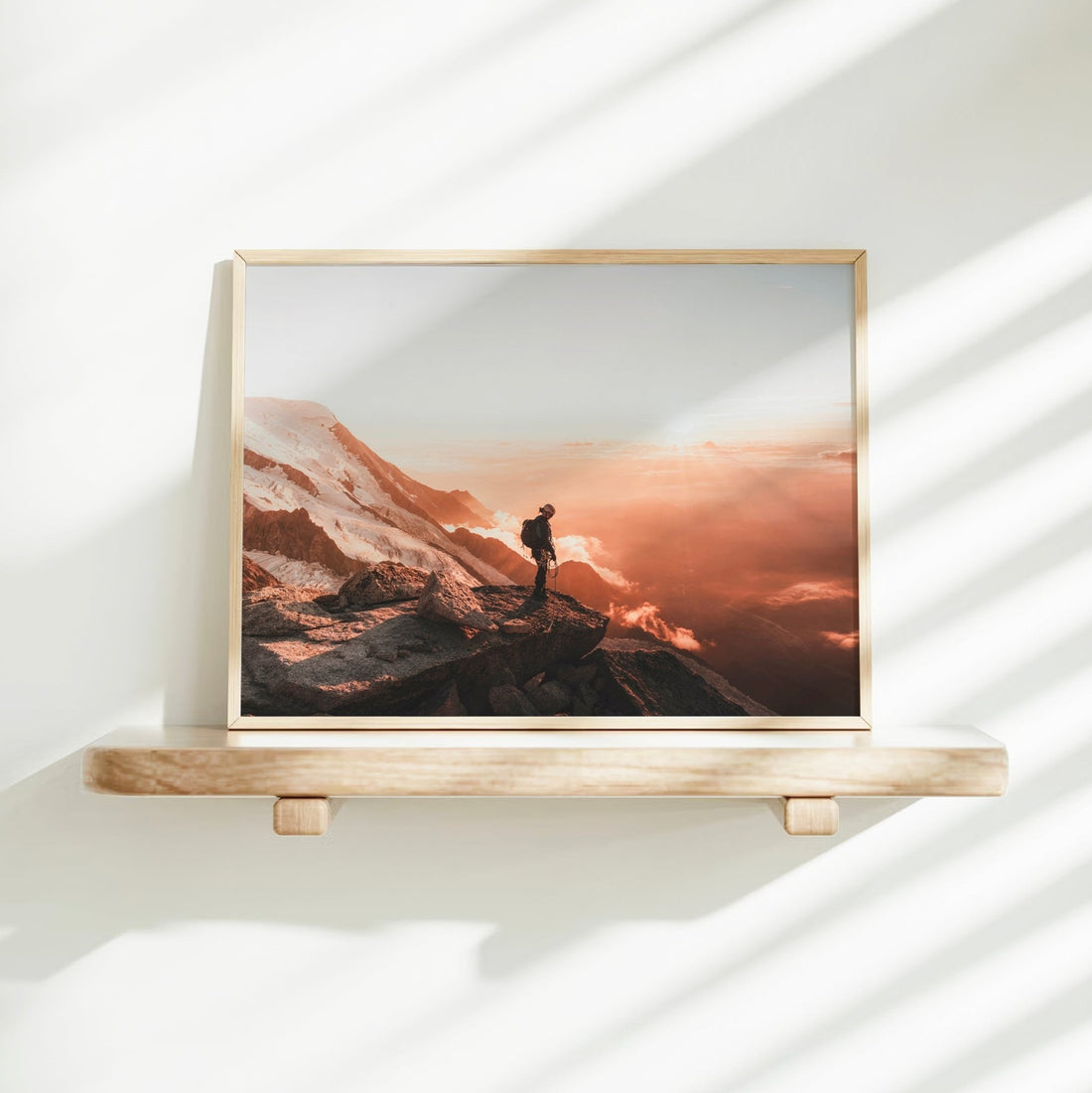 Sunset mountain adventure photography print featuring a mountaineer in silhouette against glowing alpine clouds.