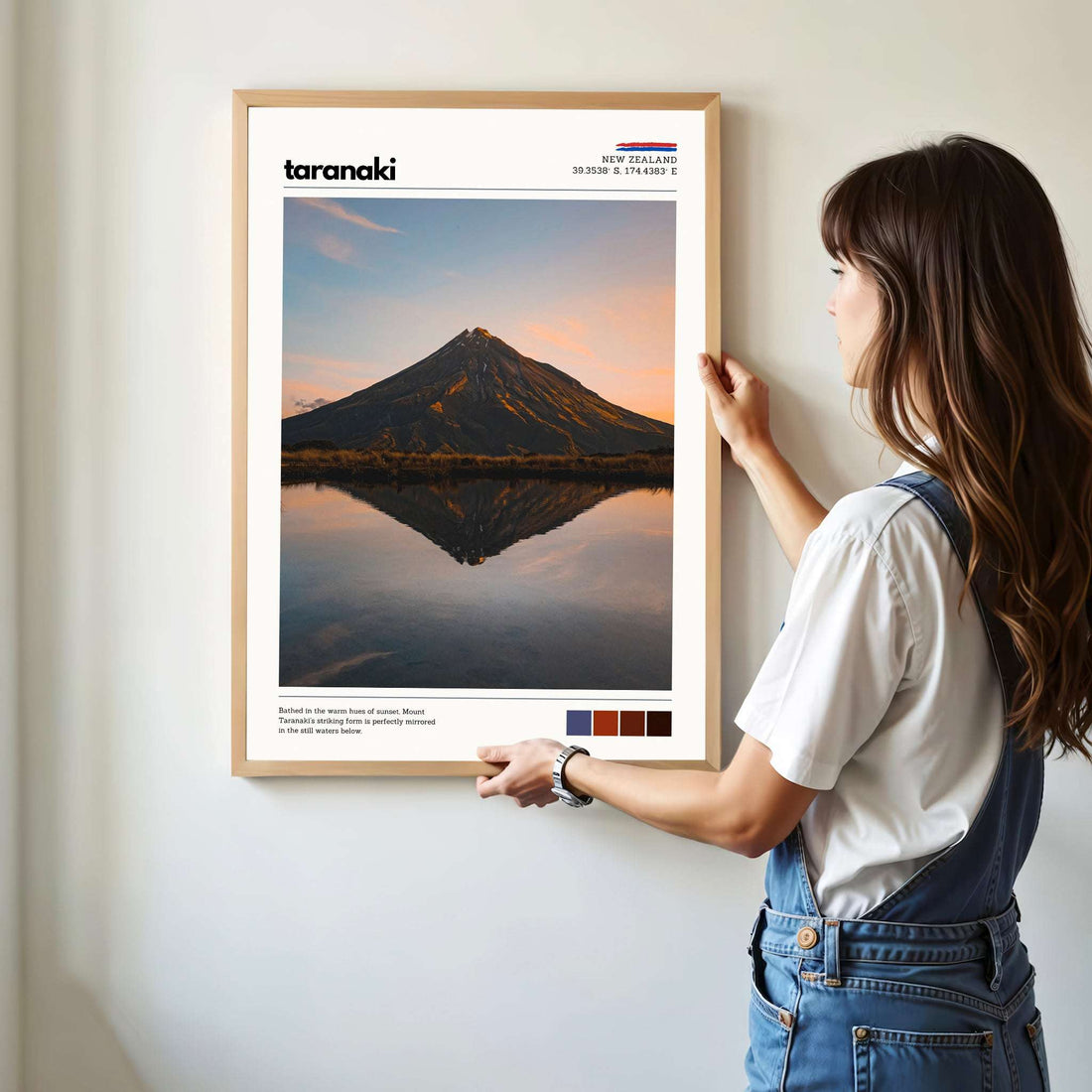 Person hanging a Mount Taranaki wall art print in a bright modern home interior