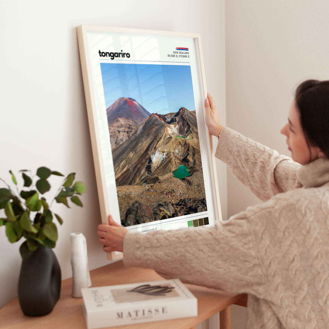 Person adjusting a framed Tongariro Crossing wall art print in a modern interior