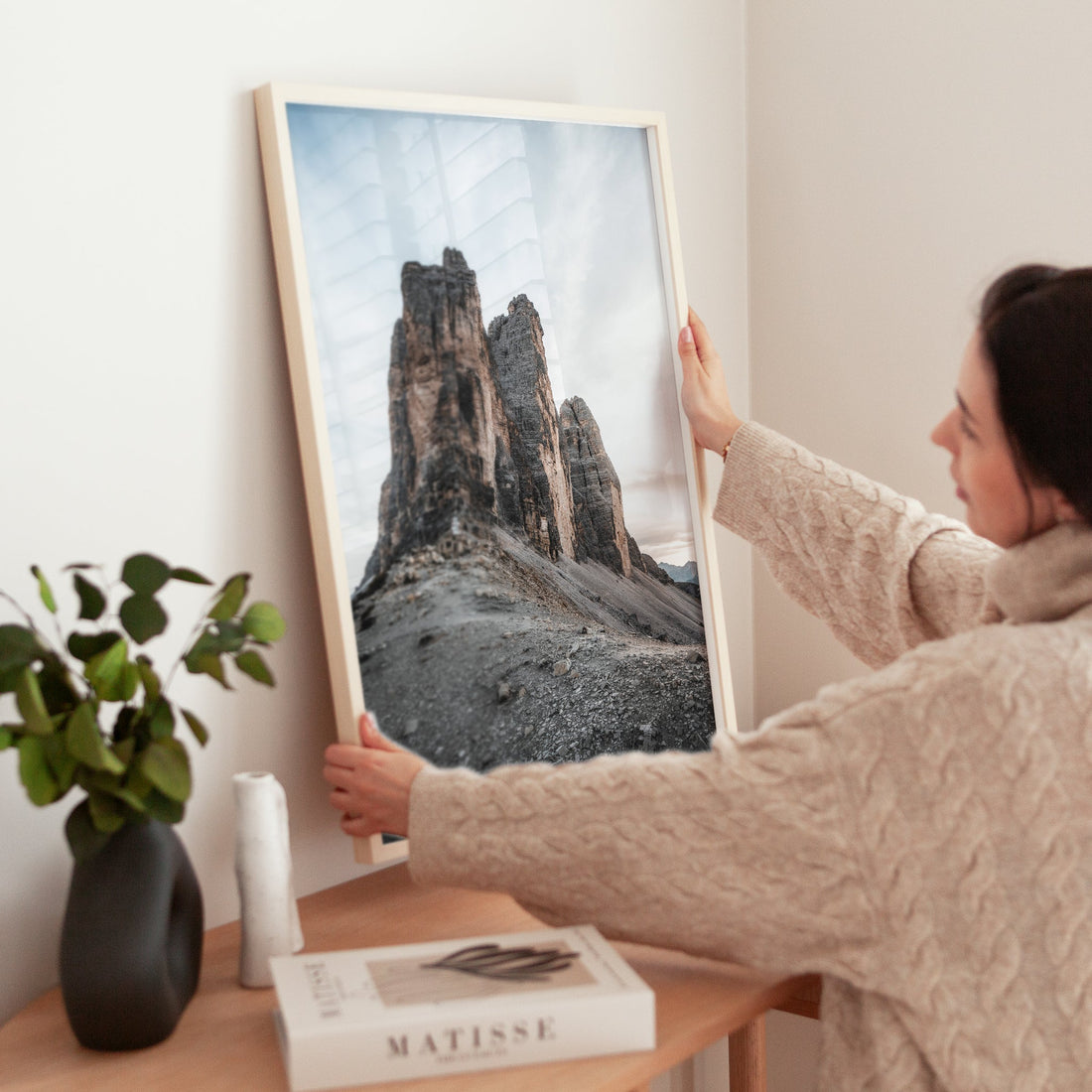 Woman holding Tre Cime photography art print in cosy living space
