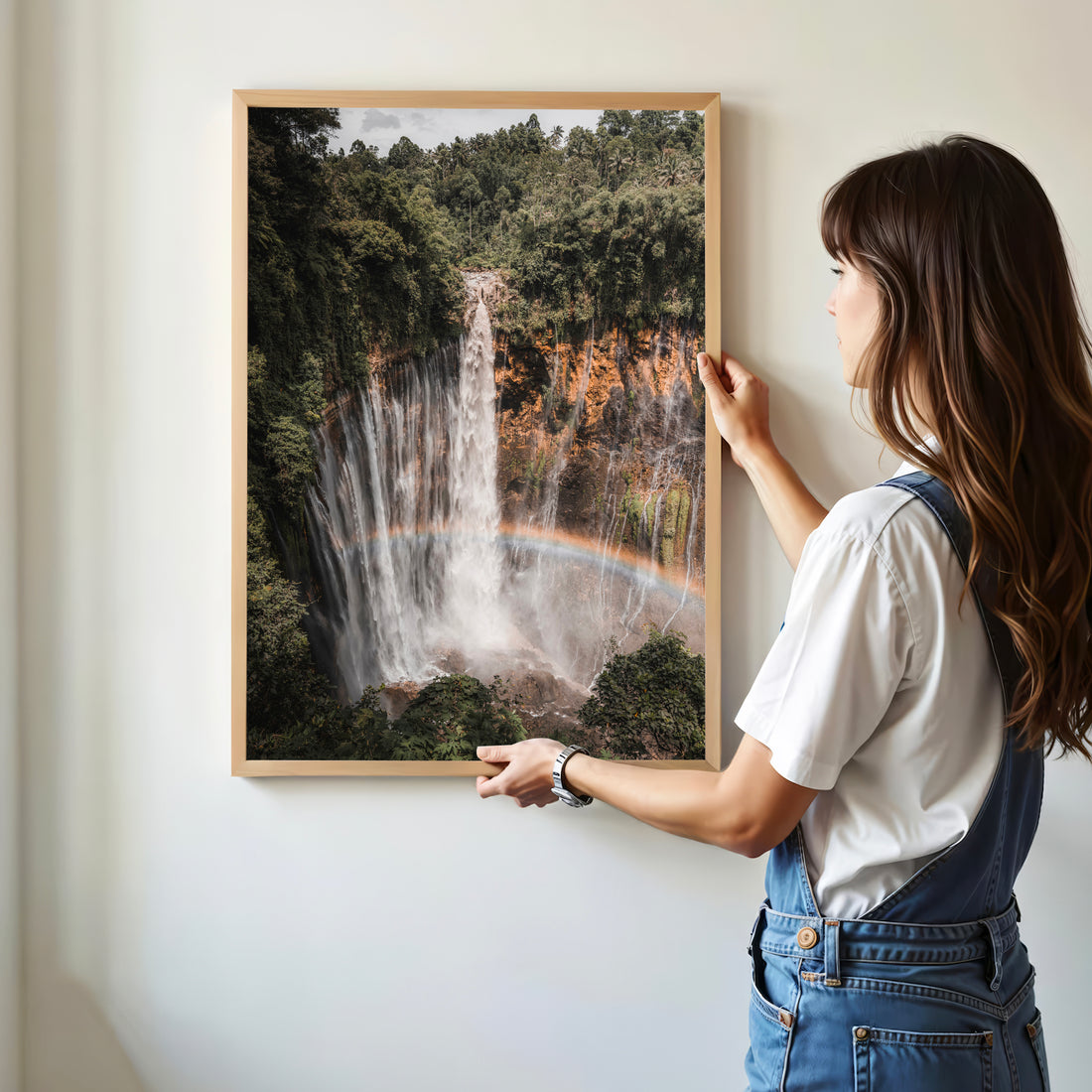 Woman holding Tumpak Sewu Waterfall wall art print in a living room