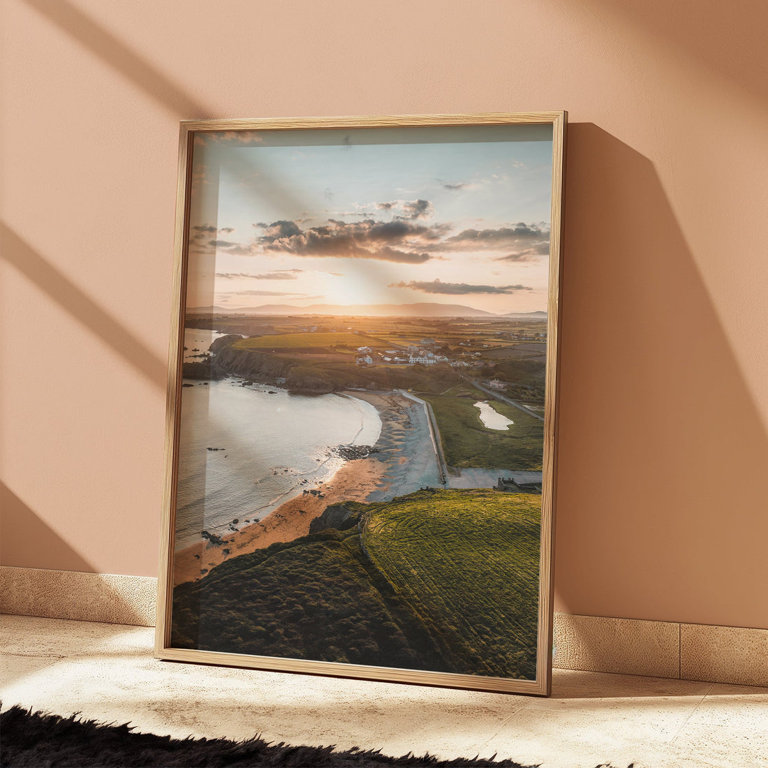 Framed Annestown Beach print leaning against a peach wall with strong sunlight