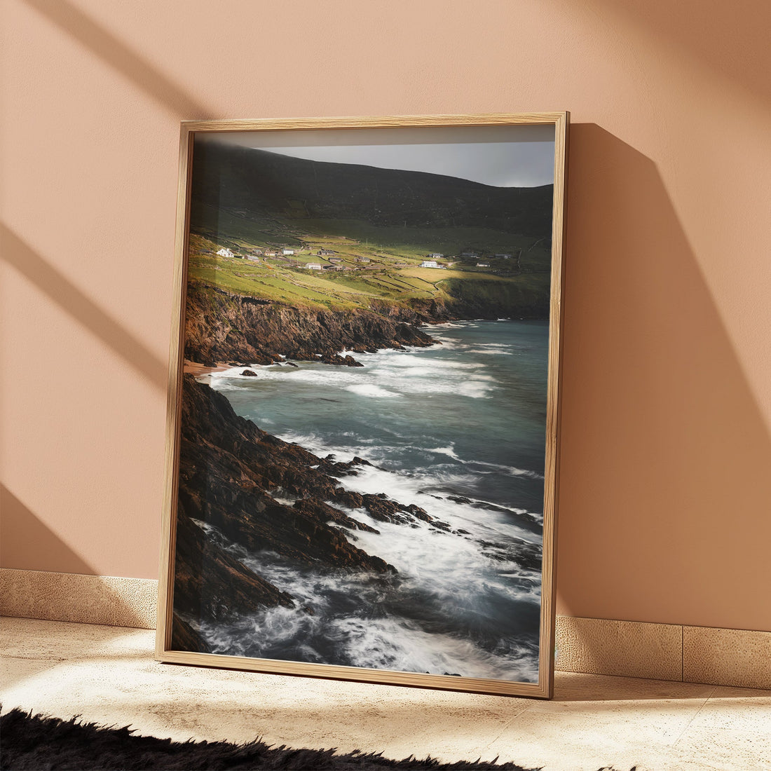 Sunlit framed art print of Coumeenoole Beach leaning against a peach wall.
