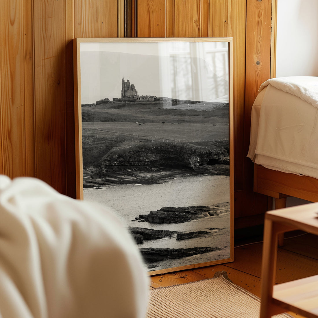 Framed black and white Classiebawn Castle artwork leaning in wooden bedroom