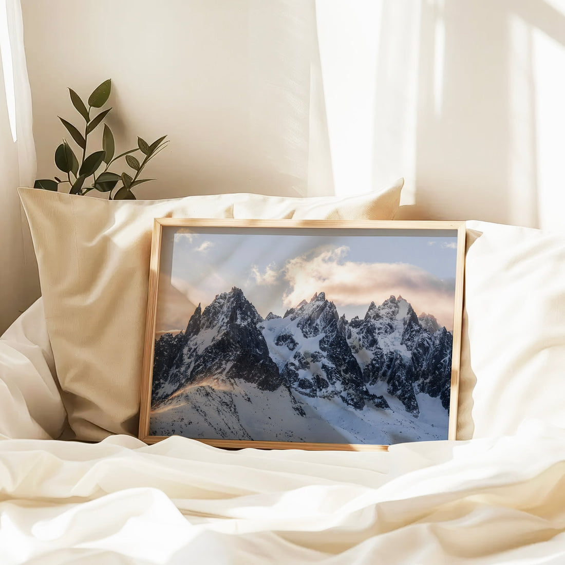 Framed snowy peaks photo print placed on white sheets with natural light