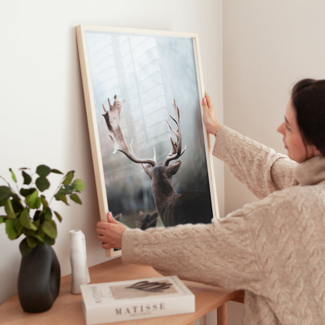 Woman decorating her home with a Bavarian deer art print