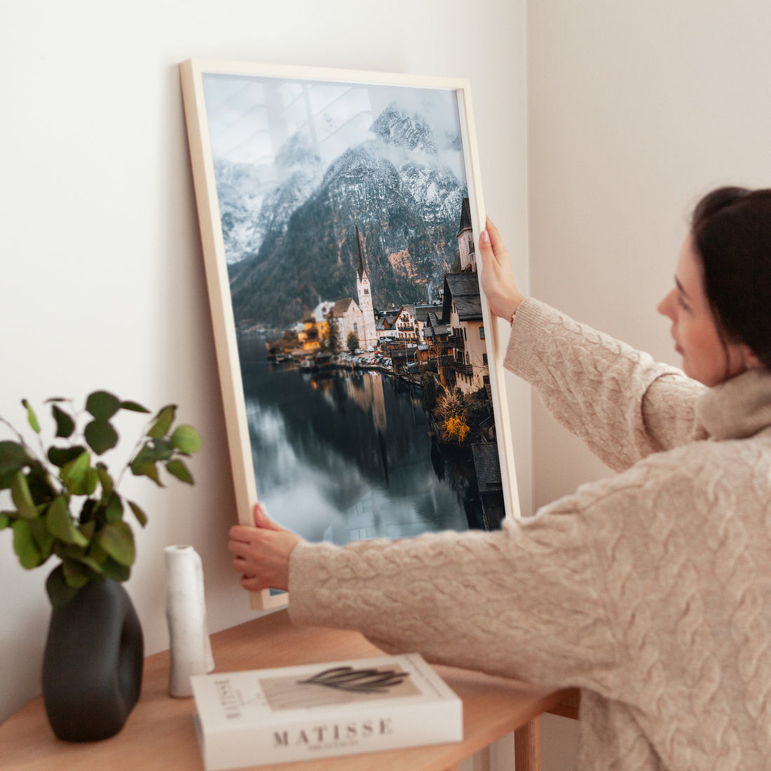 Woman decorating space with Hallstatt Austria landscape print